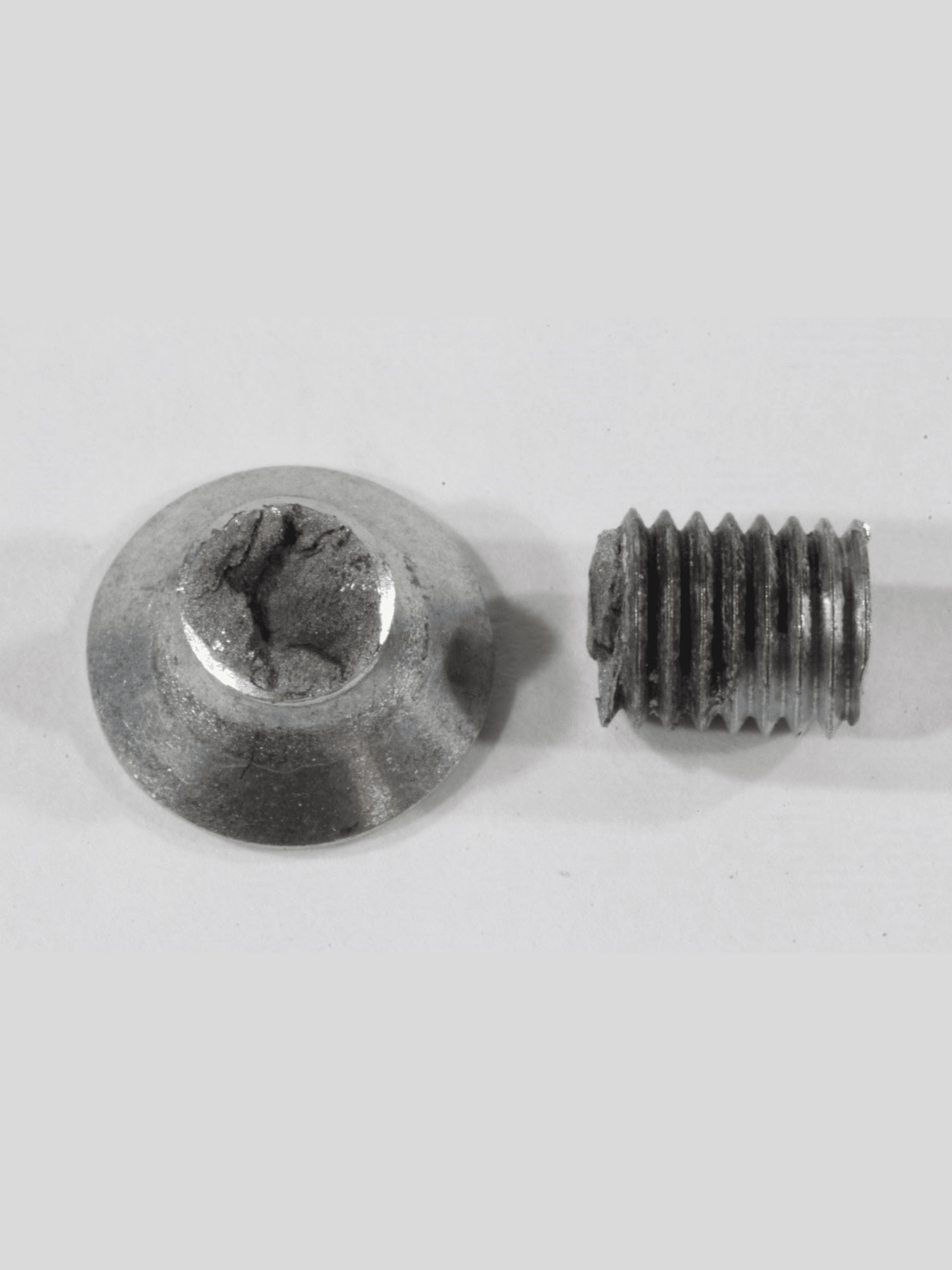 Fractured countersunk screw showing the separated screw head and threaded shank after mechanical failure.