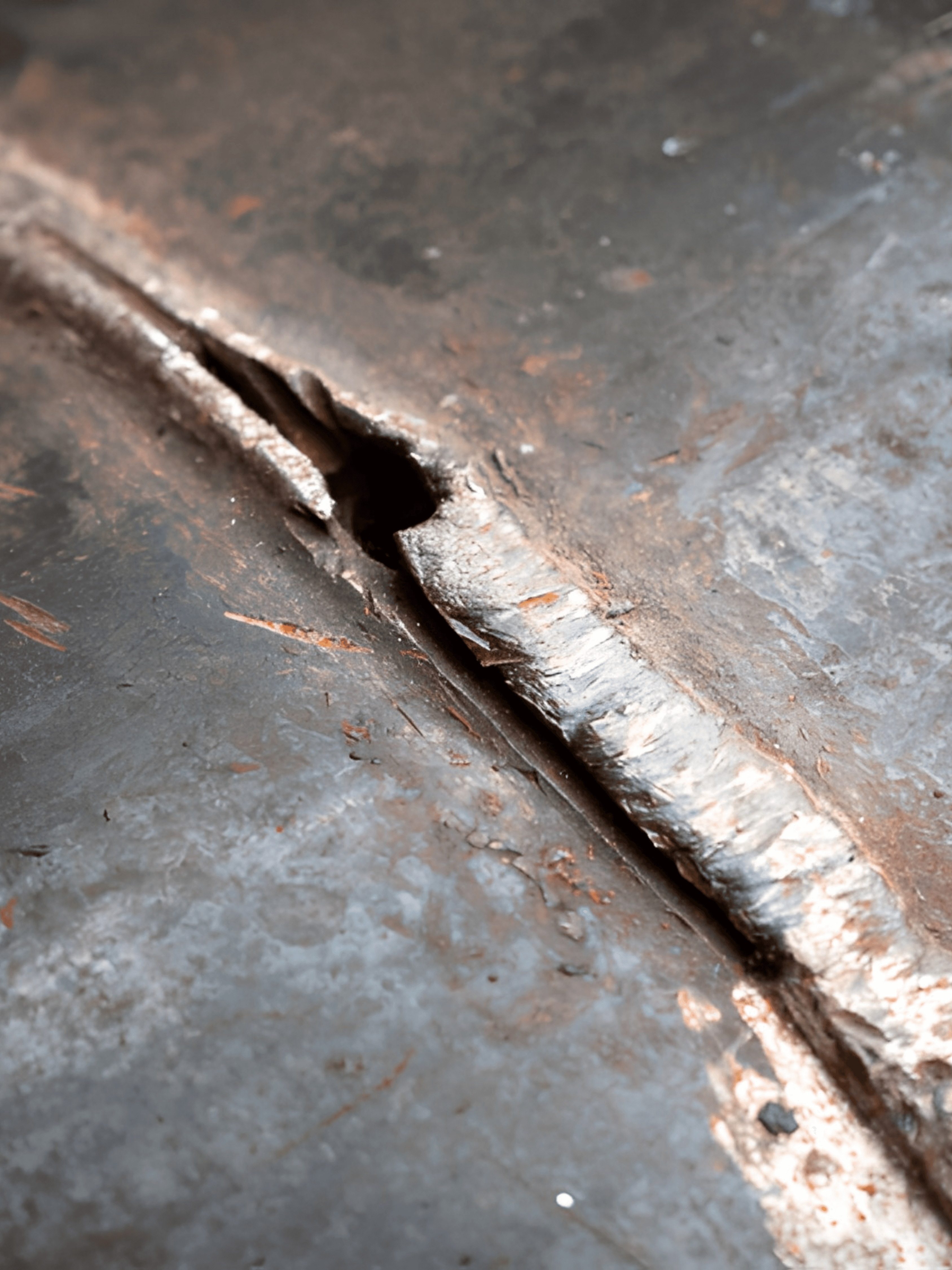 Close-up of a cracked welded steel joint showing fracture and material separation along the weld seam.