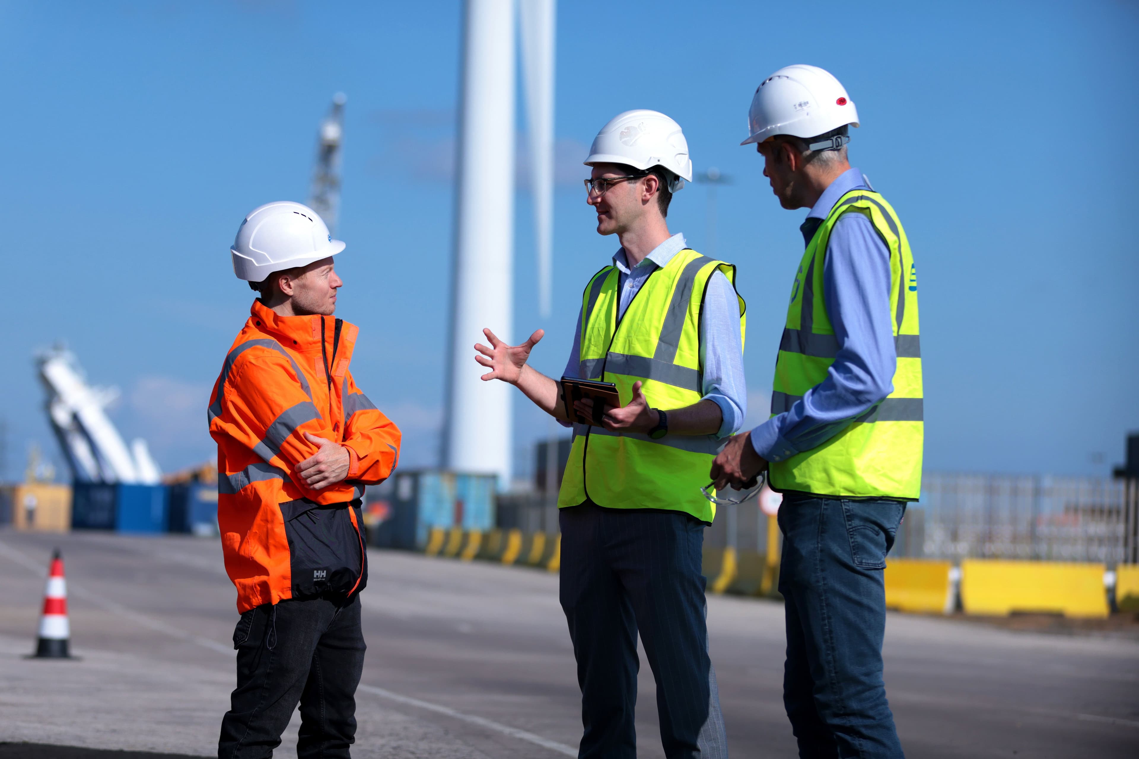 Three Subco Engineers at the Port of Blyth with a Wind Turbine in the background
